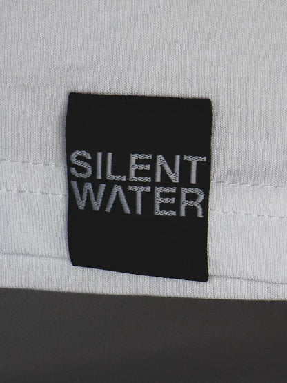 schwarzes Silent Water Badge auf weißem Shirt